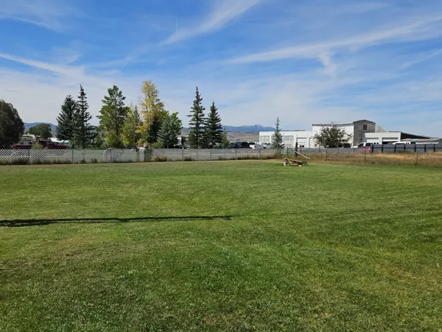 Expansive green lawn with a white chain-link perimeter fence