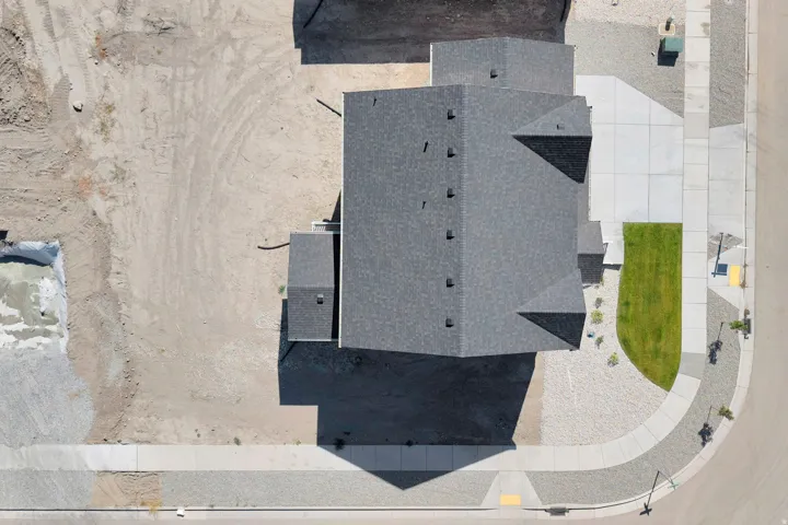 New construction residence featuring a grey shingle roof, concrete driveway, and established front landscaping with a green lawn
