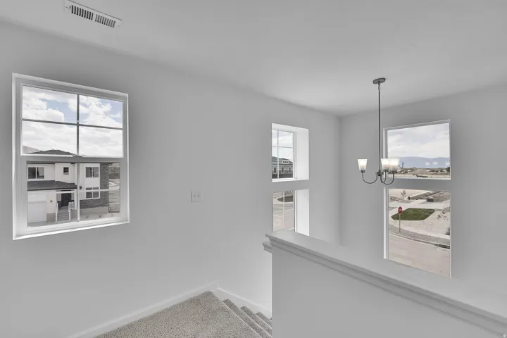 Stairwell featuring multiple windows, a contemporary chandelier, and carpeted stairs