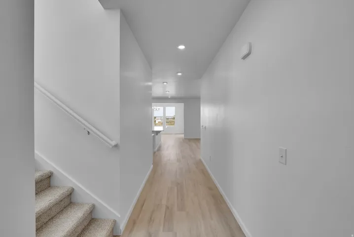 Recessed lighting, wood-finish flooring, carpeted staircase, white walls, and white trim