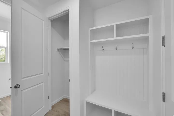 Built-in storage bench with overhead shelving, coat hooks, and wood-finish flooring