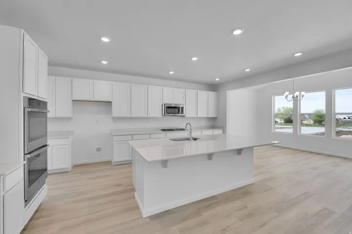White shaker cabinetry, light wood-finish flooring, recessed lighting, double wall oven, and a kitchen island with seating