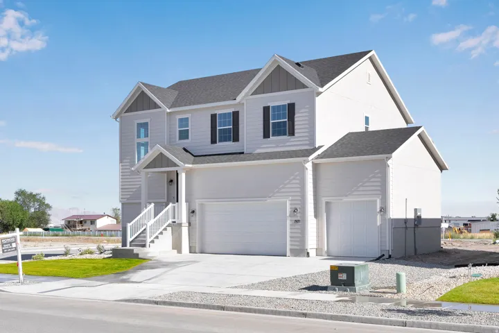 Two-story residence featuring light gray siding, dark shingle roofing, and a two-car garage