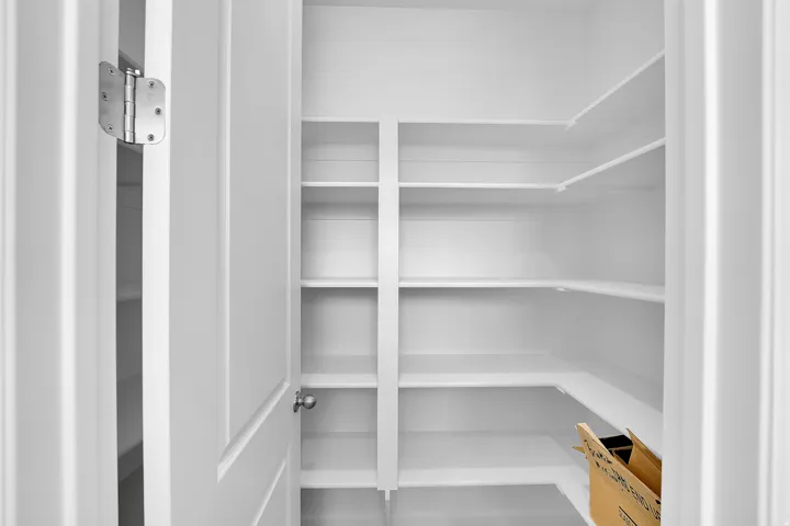 Spacious pantry with multiple built-in shelves and a white painted finish