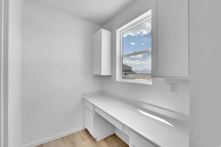 Dedicated workspace featuring built-in cabinetry, expansive countertop, and a large window
