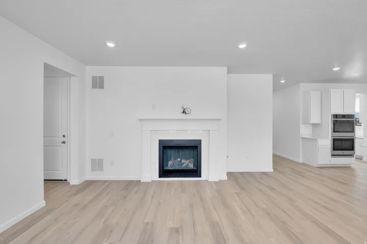 Living area featuring a fireplace with a white mantel, recessed lighting, and wood-finish flooring