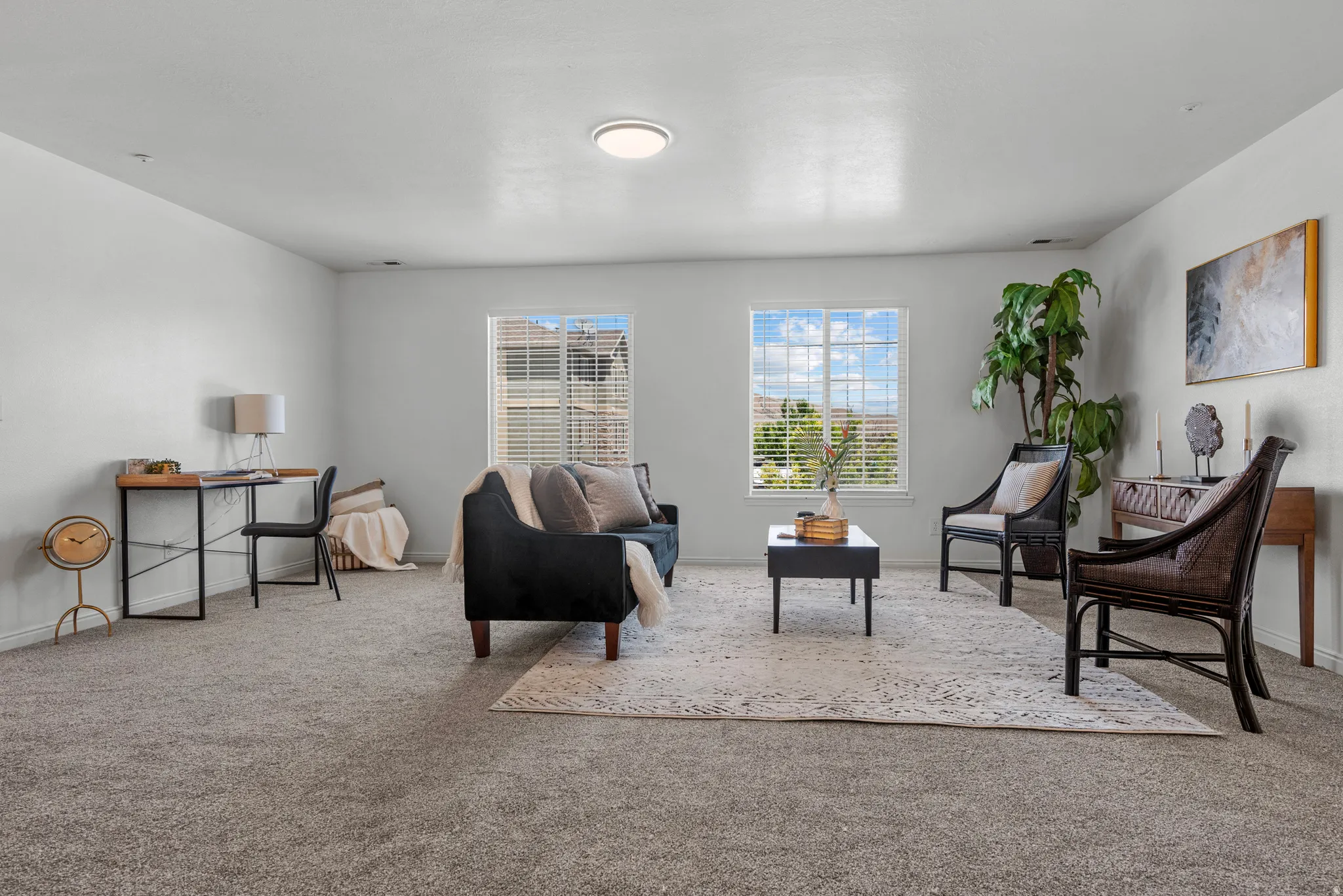 Spacious living area featuring soft gray carpeting, white walls, and a ceiling-mounted light fixture