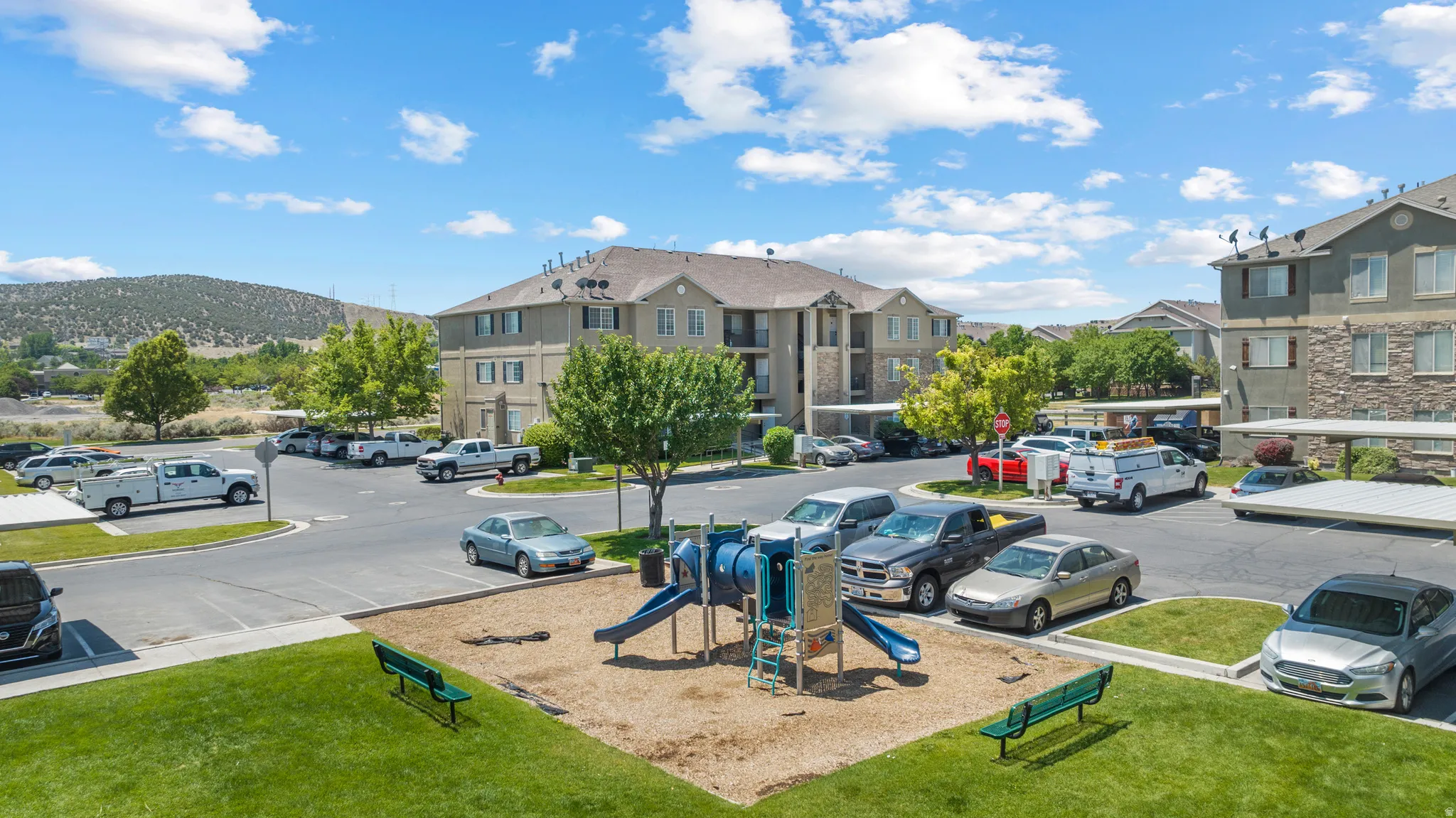 Community playground, paved parking areas, covered parking structures, and multi-story residential buildings