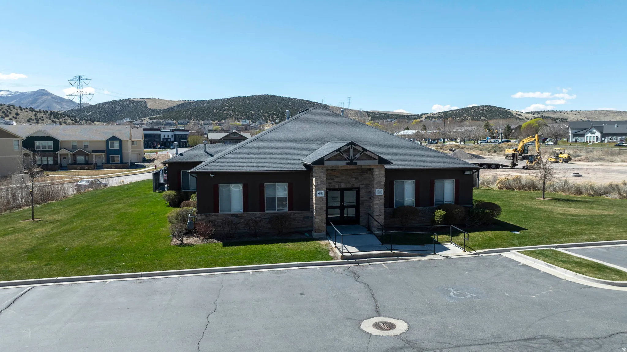 Single-story commercial building featuring a dark shingle roof and stone facade accents