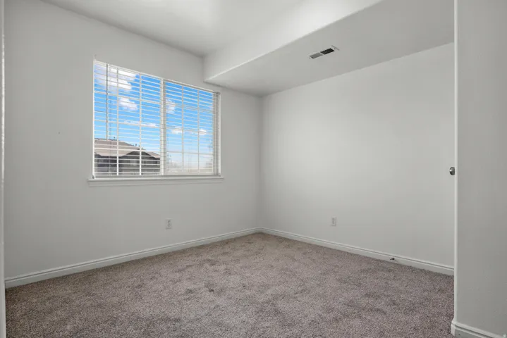 Recessed window with horizontal blinds, neutral wall paint, and gray carpet flooring