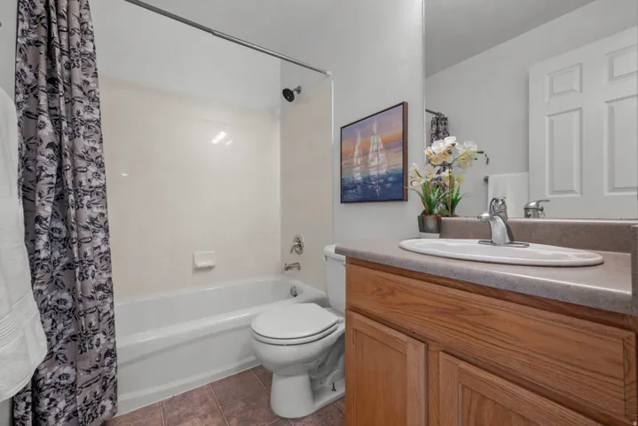 Bathroom featuring a white bathtub, shower with a dark finish showerhead, and a vanity with wood-finish cabinetry