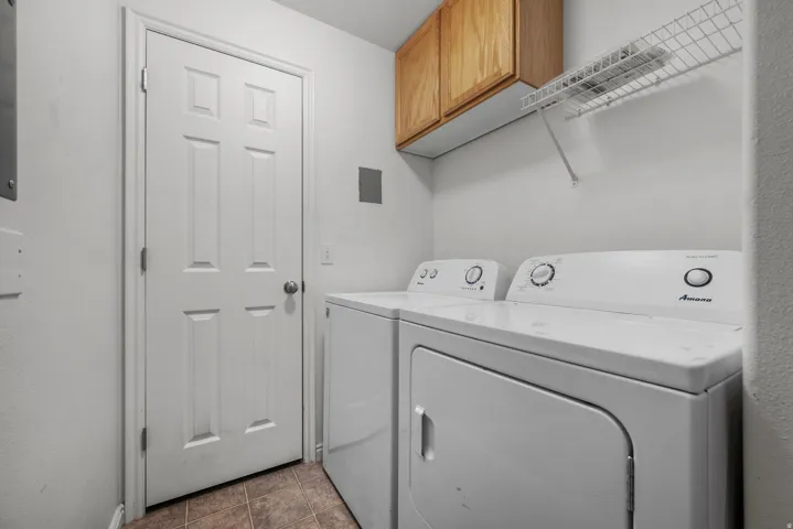 Laundry area featuring wood-finish cabinetry, a wire shelf, and tile flooring