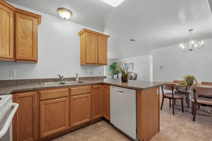 Kitchen featuring wood cabinetry, laminate countertops, a stainless steel sink, and tile flooring