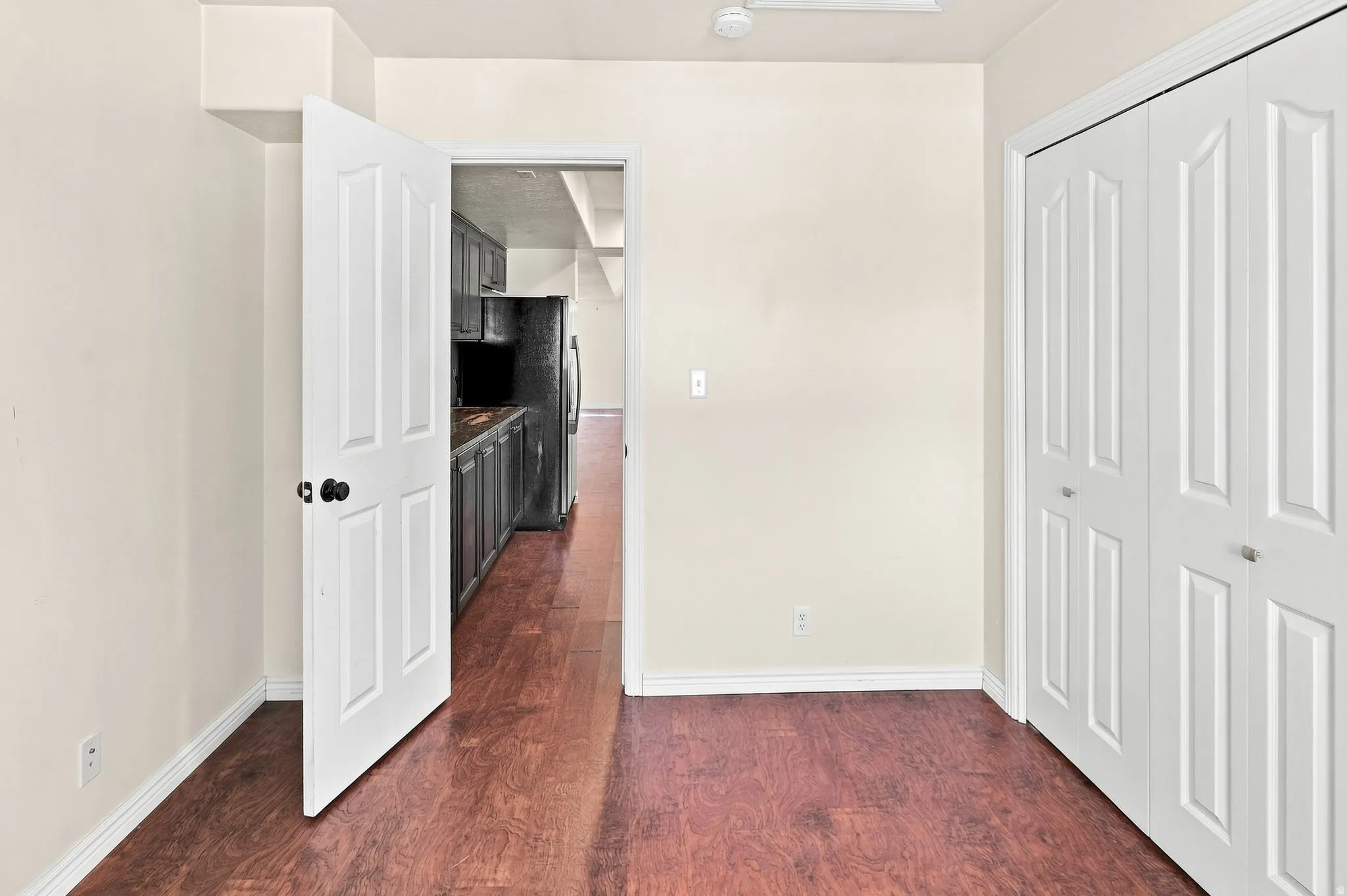 Wood-finish flooring throughout, bright white walls, and a white bi-fold closet door