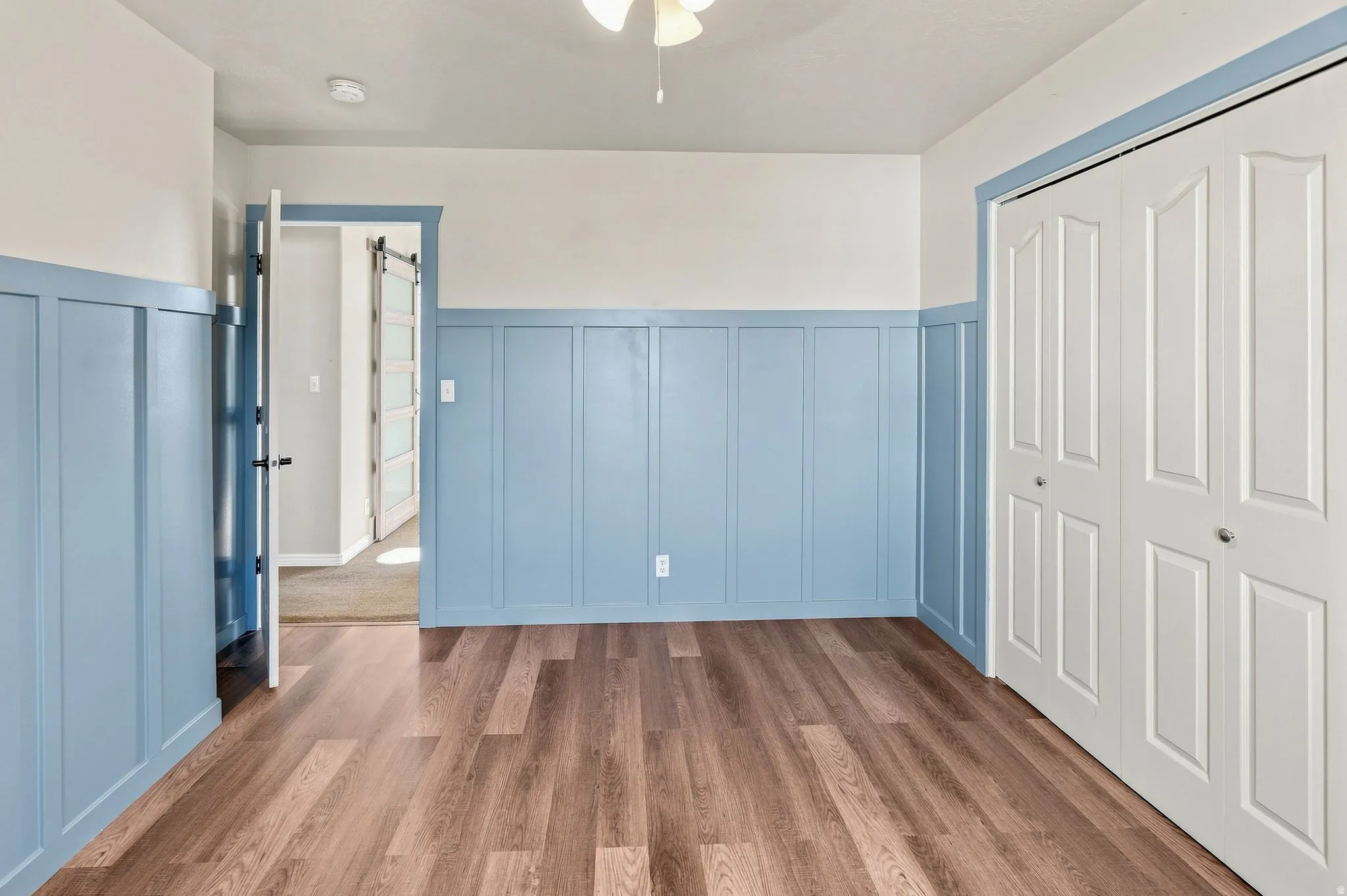 Wood-finish flooring, half-wall wainscoting, white bi-fold closet doors, and recessed lighting