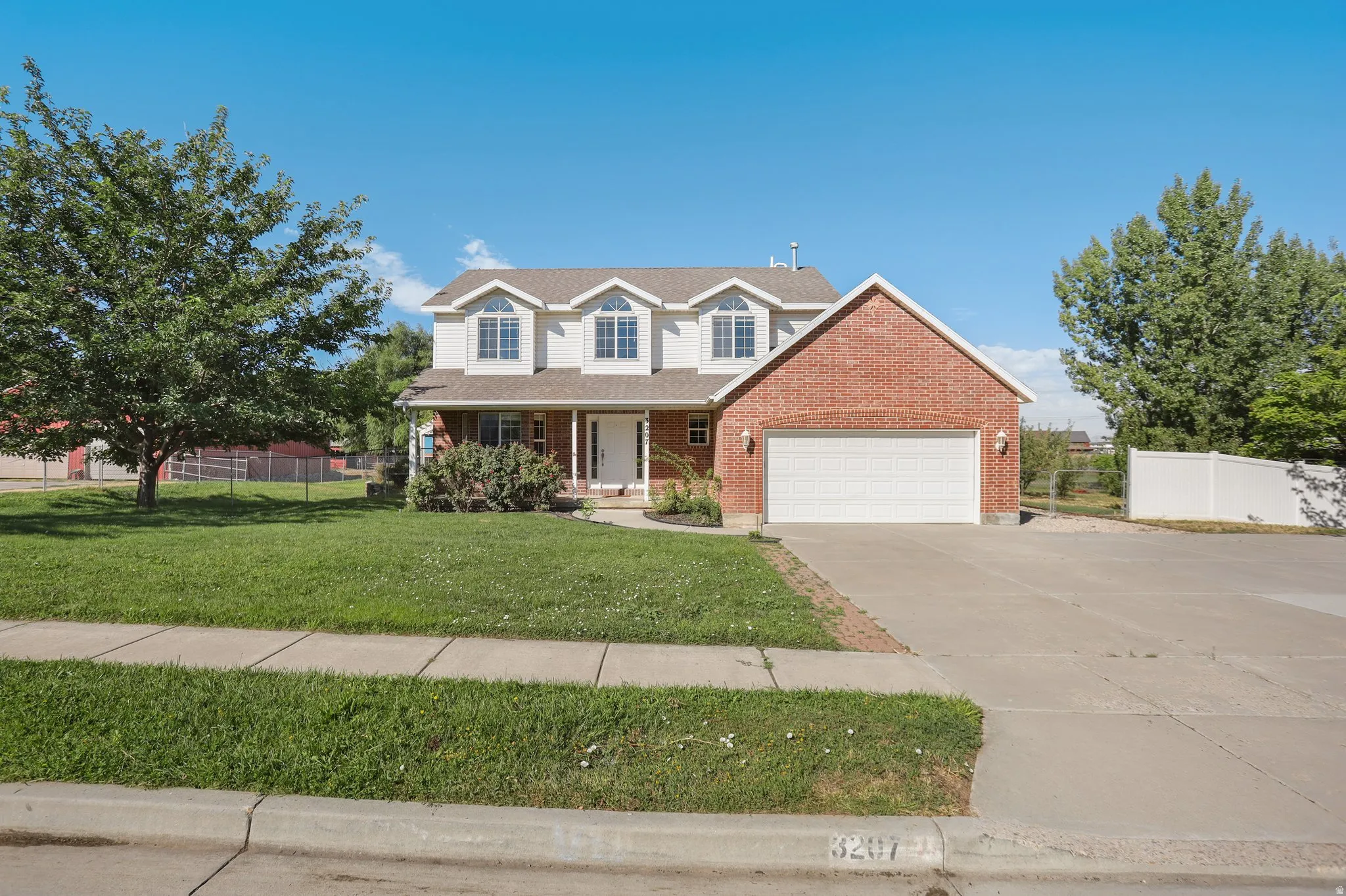 Two-story residence featuring a brick and siding exterior, an attached two-car garage, and a concrete driveway