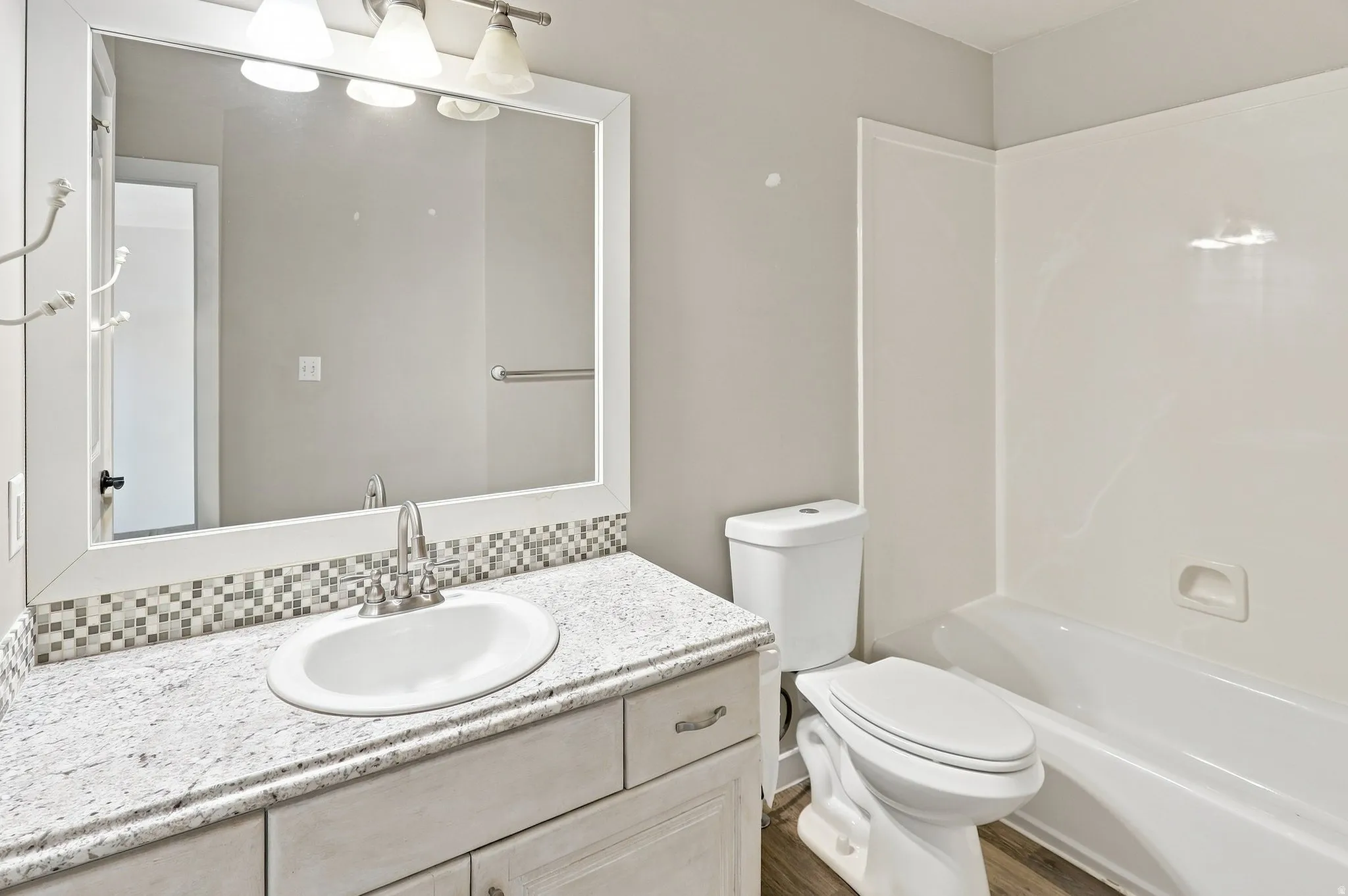 Vanity with a polished countertop, undermount sink, and mosaic tile backsplash