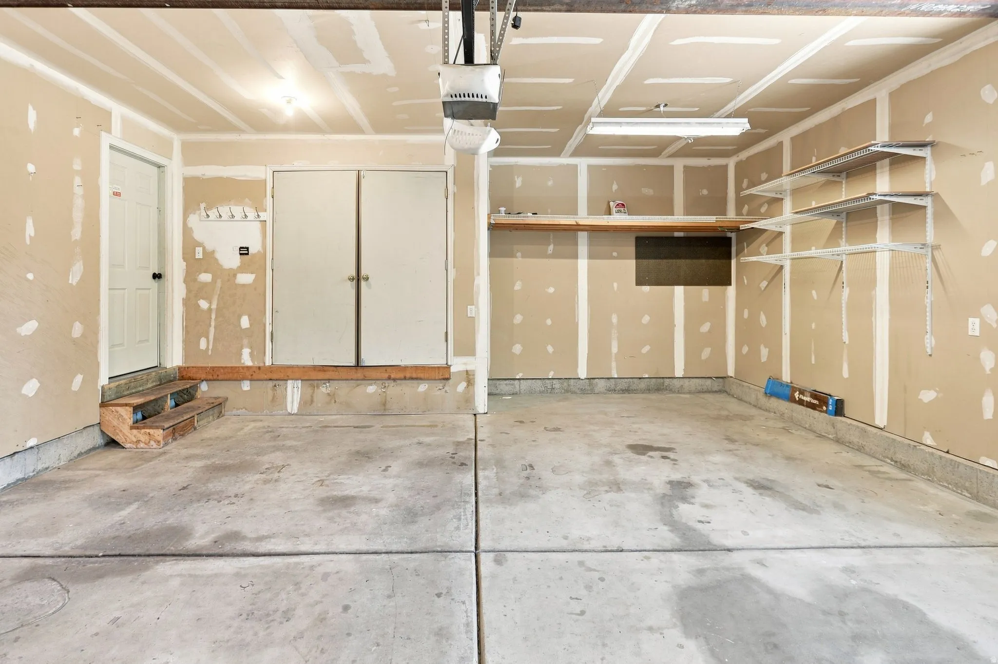 Concrete flooring, built-in shelving, overhead lighting, and interior access doors