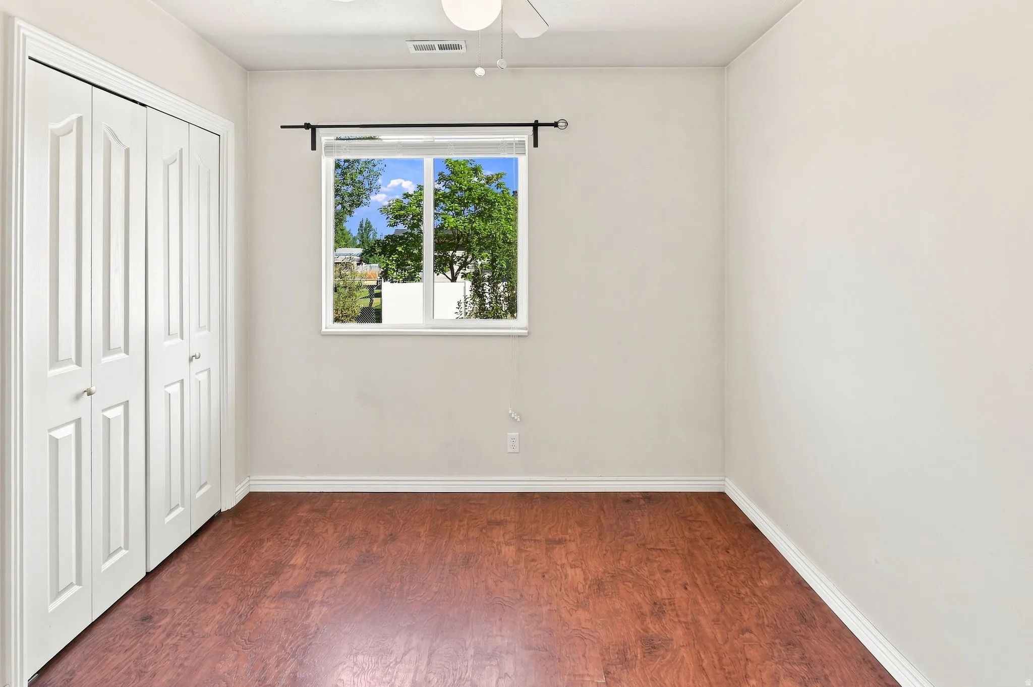 Wood-finish flooring, white walls, and a window with white trim