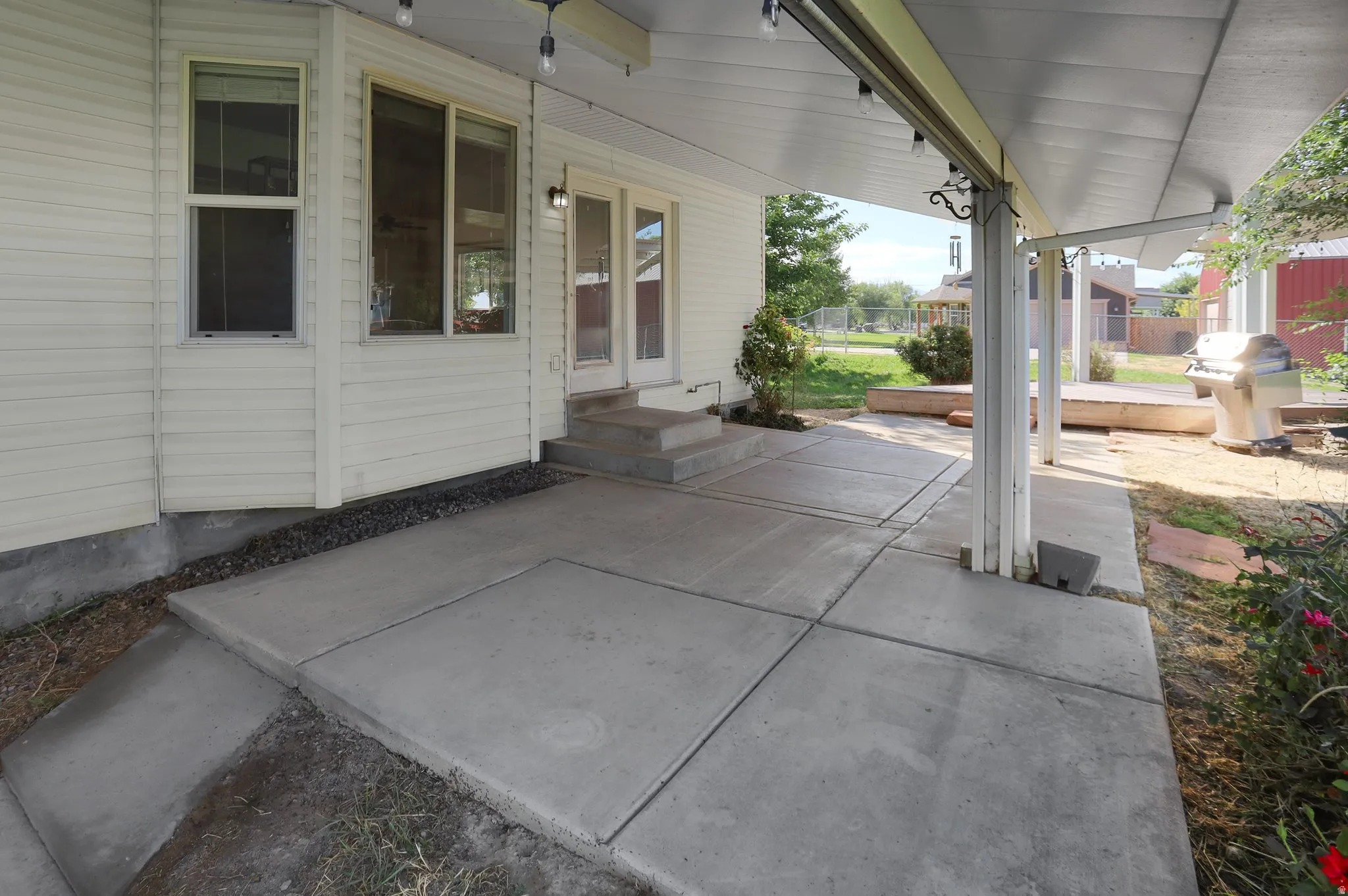 Expansive concrete patio with a covered outdoor area, dual pane windows, and a glass-paneled door
