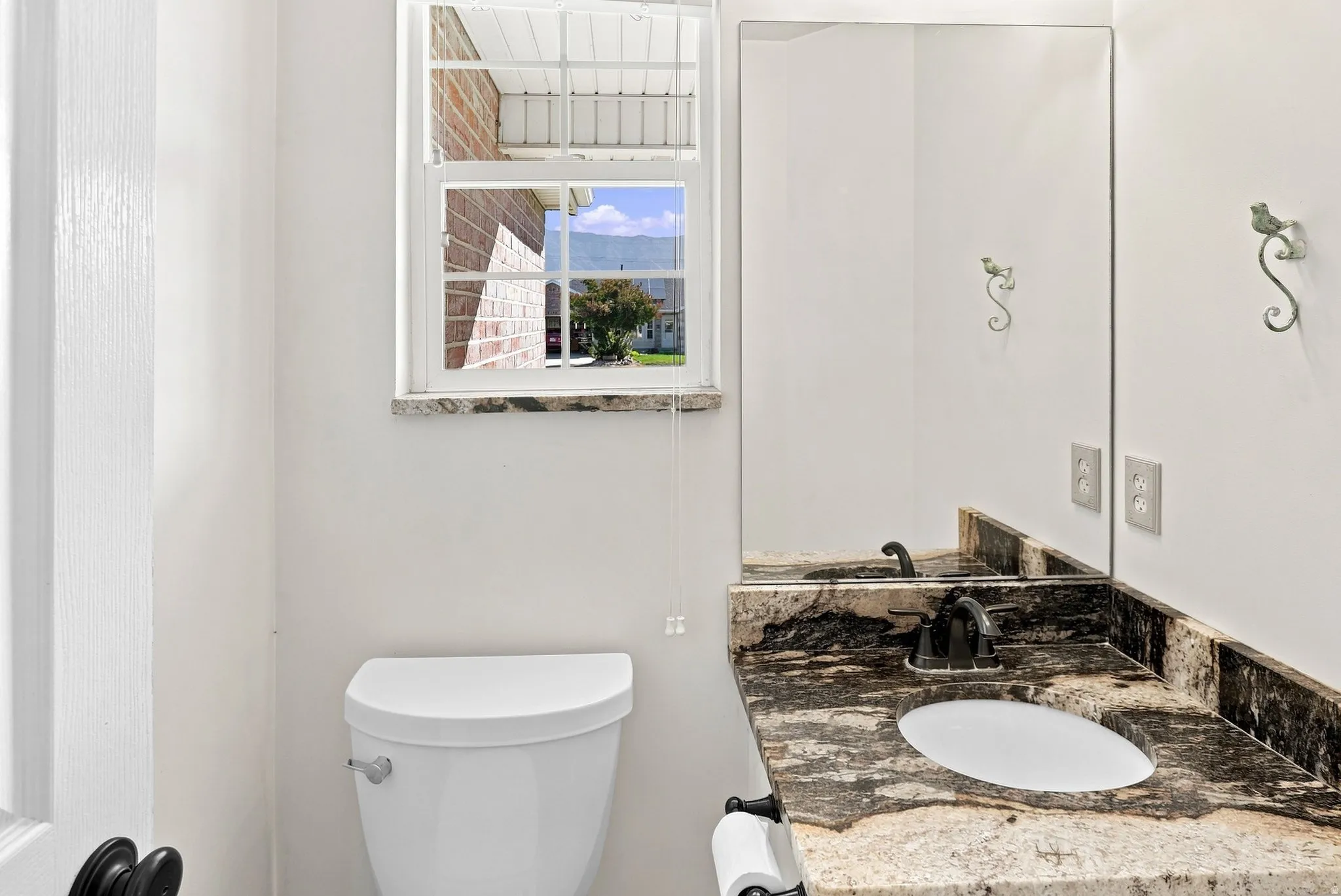 Vanity with a polished stone countertop, integrated sink, and dark-toned faucet