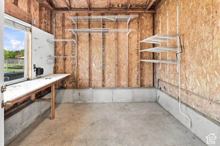 Concrete flooring with a built-in workbench, pegboard, and multiple wall-mounted shelving units