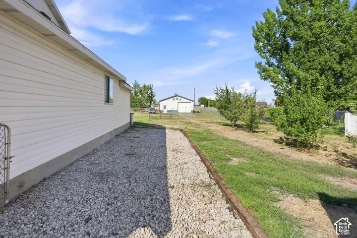 Property exterior featuring horizontal siding and a gravel perimeter, complemented by a grassy area with established trees