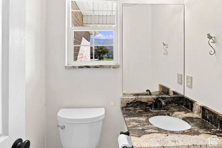 Vanity with a polished stone countertop, integrated sink, and dark-toned faucet