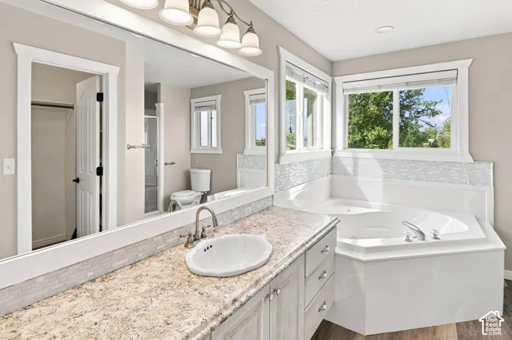 Dual-sink vanity with a light-toned countertop, mosaic tile backsplash, built-in bathtub, and an expansive mirror