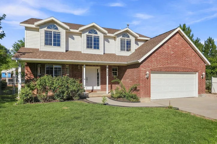 Brick and siding exterior with a covered front porch, an integrated garage, and arched dormer windows