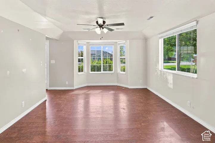 Spacious room featuring wood-finish flooring, light-toned walls, and multiple windows