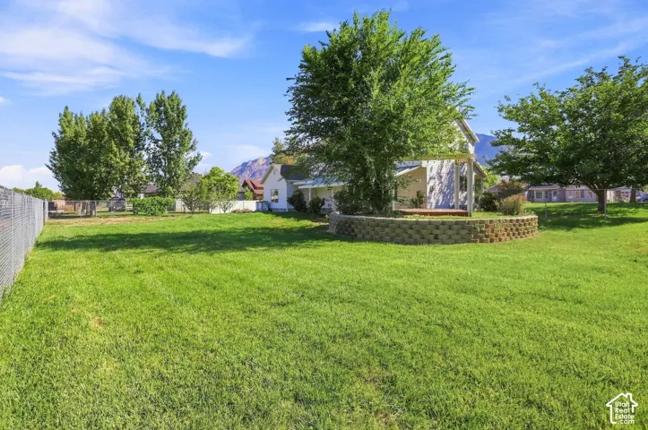 Expansive lawn area featuring mature trees and a decorative stone retaining wall
