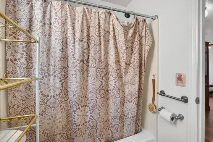 White tub with a shower rod and an adjacent towel bar
