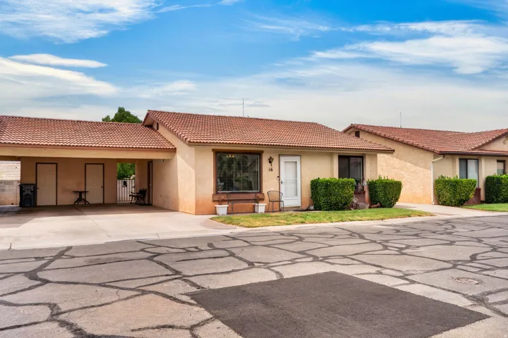 Stucco exterior with a terracotta-style tile roof, front landscaping, and a covered carport