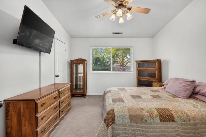 Recessed window with blinds, ceiling fan with integrated lighting, white walls, and carpeting throughout