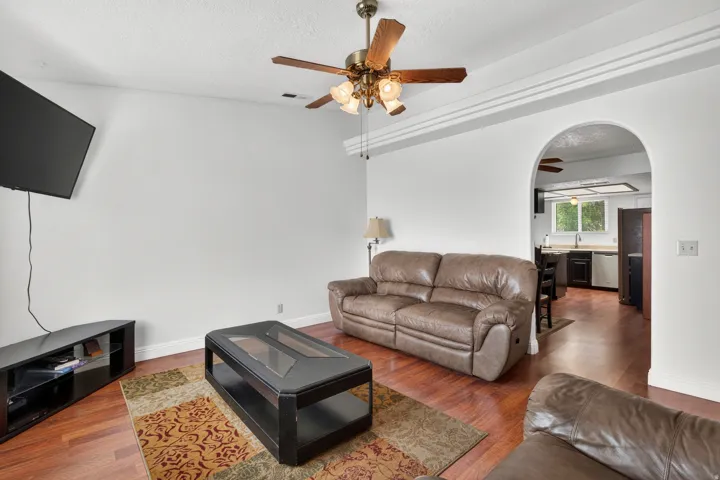 Vaulted ceiling featuring a ceiling fan with integrated lighting, wood-finish flooring, and an arched entryway