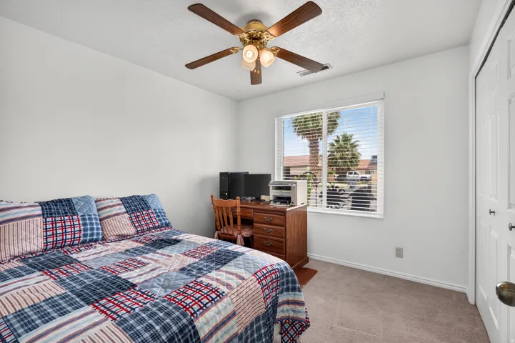 Window with horizontal blinds, ceiling fan with light fixture, neutral carpet flooring, and bi-fold closet doors