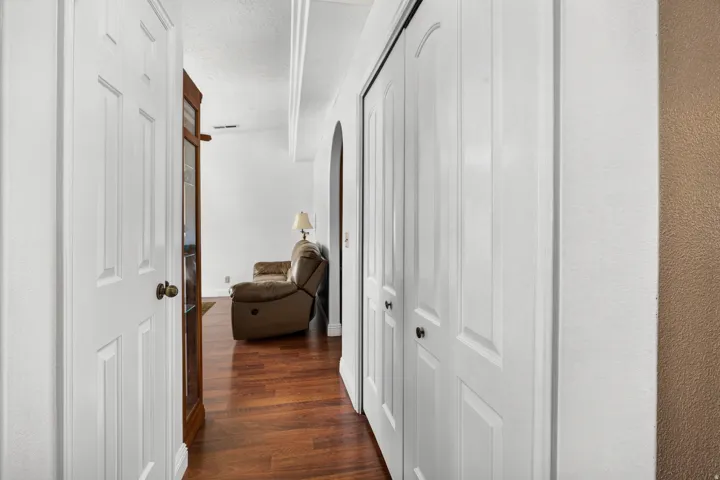 Hardwood flooring, white paneled doors, and arched entryway