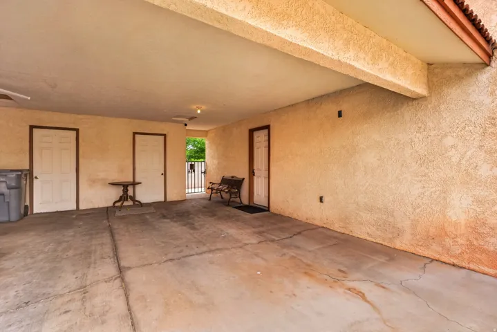 Covered carport with stucco walls, concrete flooring, and multiple entry points