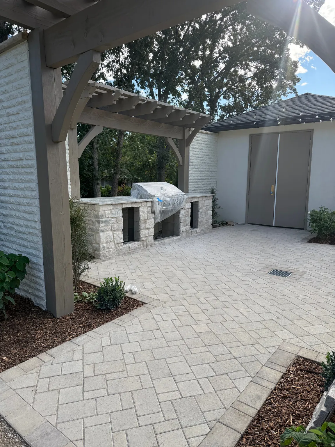 Stone paver patio featuring a wood pergola and built-in stone outdoor kitchen