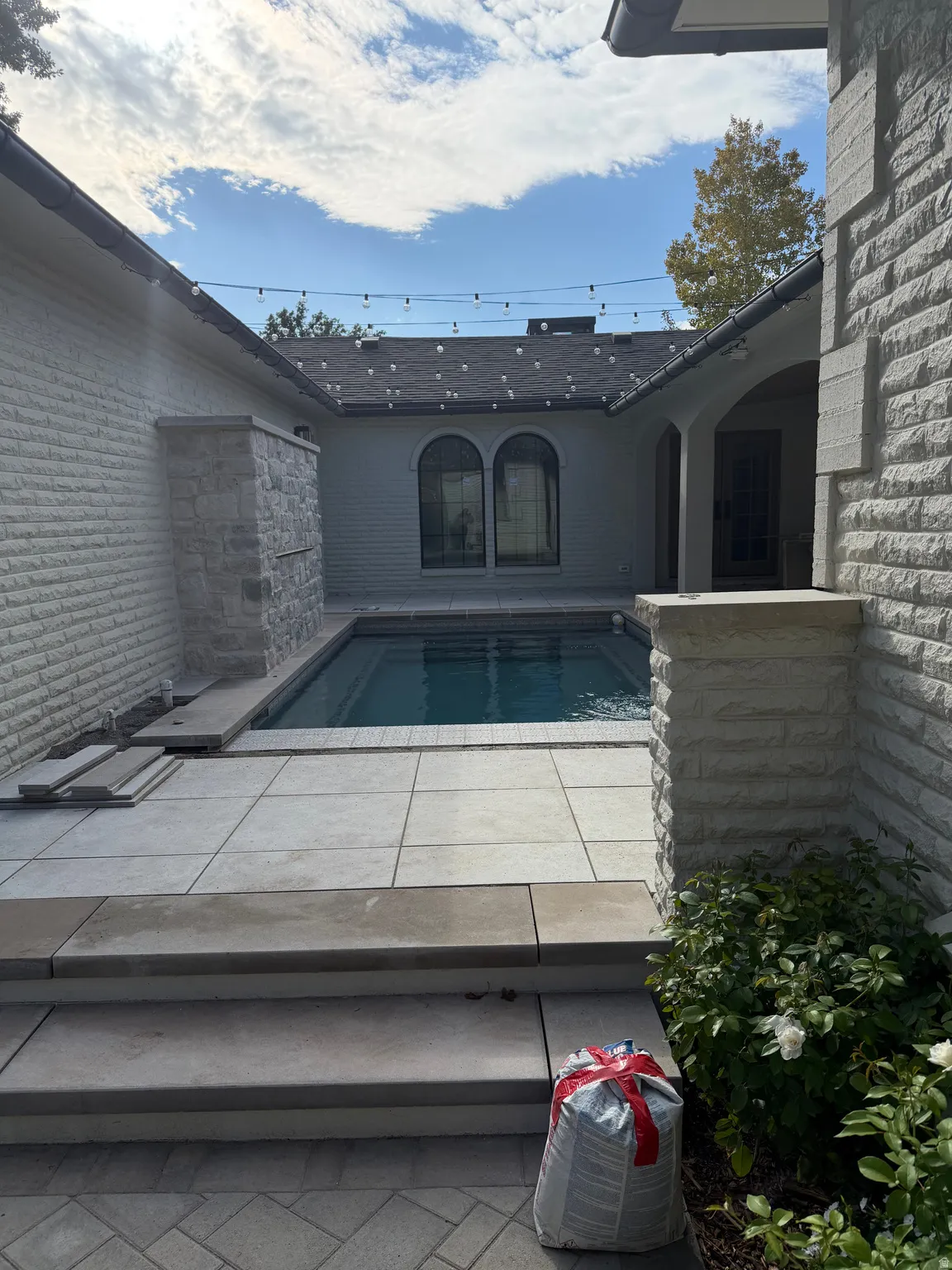 Private courtyard featuring a swimming pool, stone tile patio, and exterior brickwork