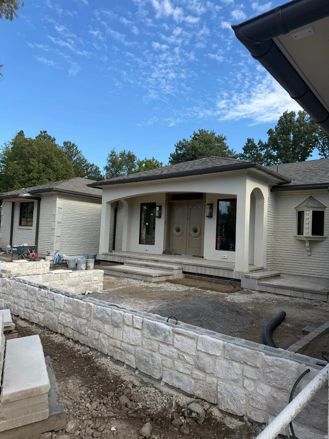 White brick exterior with a front entry porch, decorative double entry doors, and a stone retaining wall
