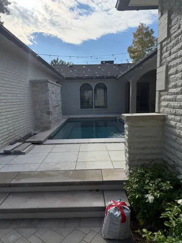 Private courtyard featuring a swimming pool, stone tile patio, and exterior brickwork