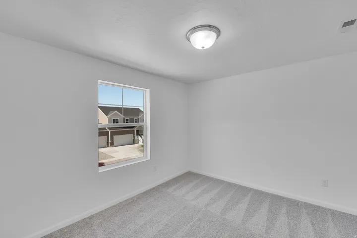 Recessed lighting, light gray carpeting, and a single window