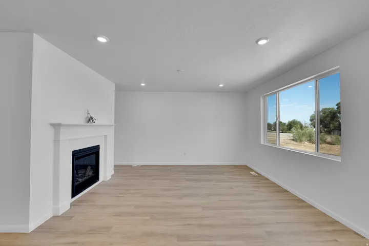 Recessed lighting, wood-finish flooring, white mantel, and a large window