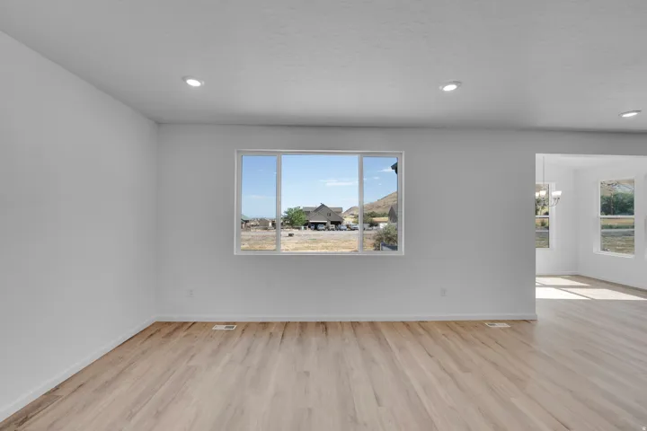 Recessed lighting illuminates an open-concept interior with wood-finish flooring and a large window