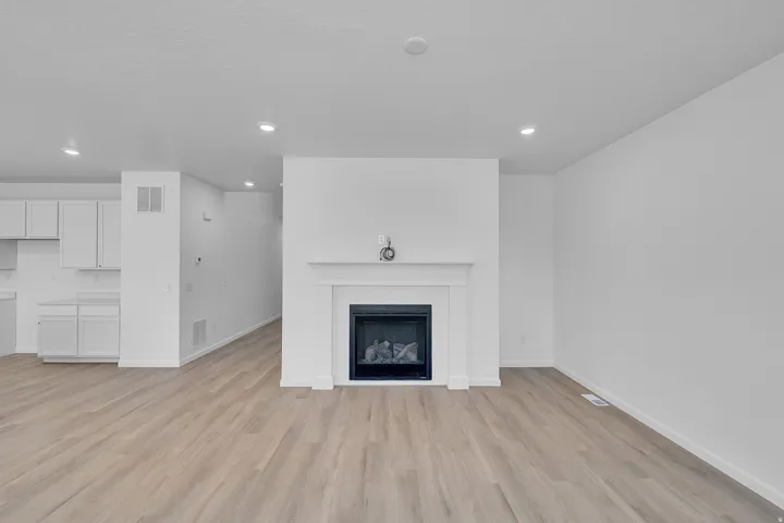 Recessed lighting illuminates the open-concept living space with wood-finish flooring