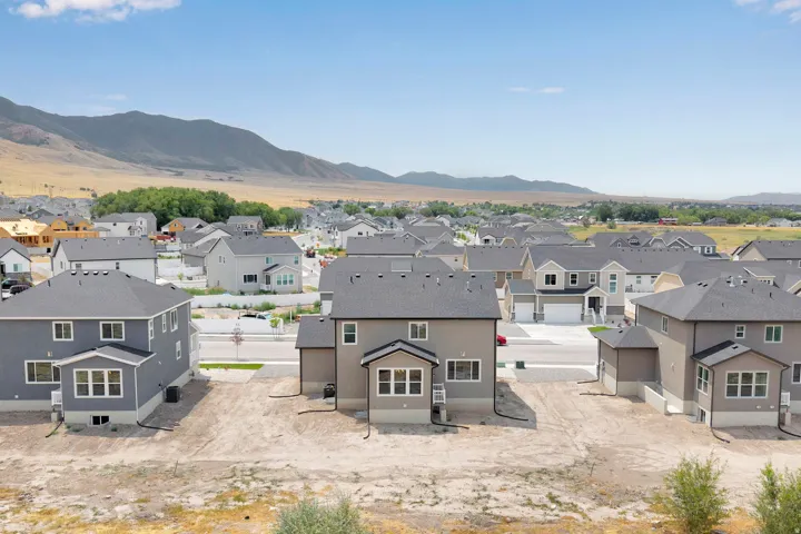 Newly constructed residence with a grey exterior, multiple windows, and a dark shingle roof