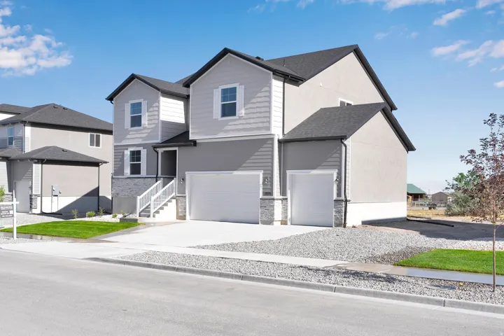 Two-story residence featuring a gray exterior with white siding accents, a two-car garage, an additional single-car garage, and a concrete driveway