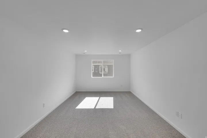 Neutral white walls, recessed lighting, and grey carpet flooring